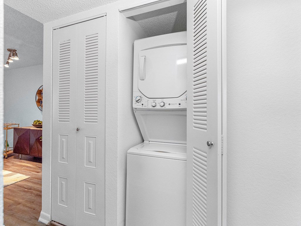 A white washing machine is installed in a white cabinet.